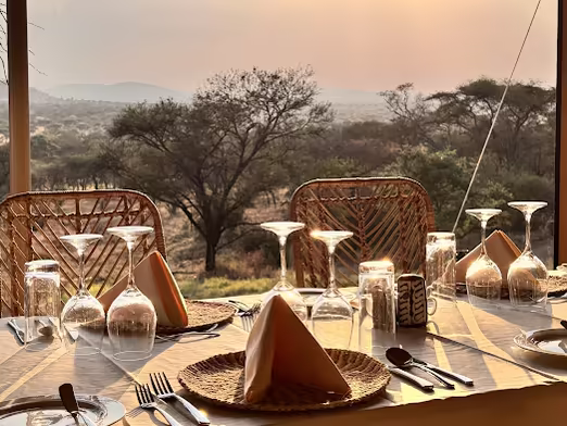 Dinner table on a deck above acacia woodland